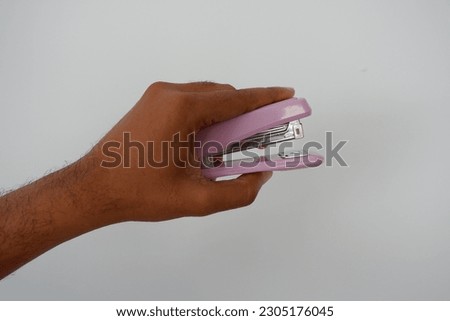 Hand holding purple staple on white background