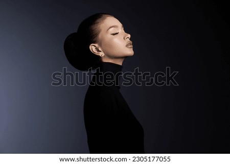 Fashion art studio portrait of beautiful elegant woman in black turtleneck. Hair high beam, perfect profile face. Elegant beauty style. Earrings in the ears