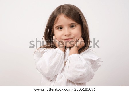 Portrait of young cute adorable smiling girl child kid hold hands under chin isolated on white color background
