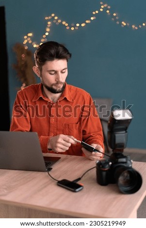 Photographer working at home office. Workflow or creative process of freelance photographer. Export or transfer data files and images photos from camera to laptop through card reader. Copy space