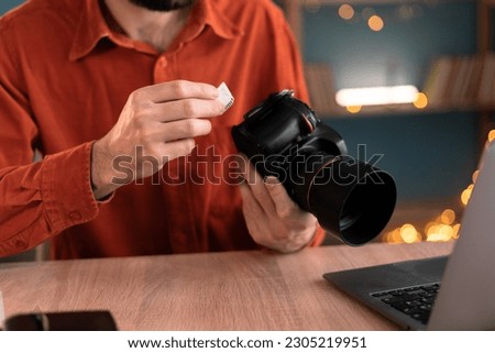 Photographer, journalist or creative creator copying photos from her camera to laptop working at home office. Hand with SD card. creative process of freelance photographer. Close-up