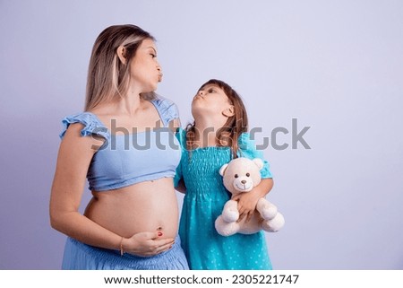 Elder sister hugging her pregnant mother holding a teddy bear