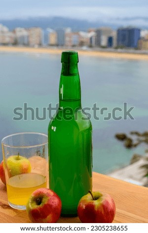 Traditional natural Asturian cider made from fermented apples in wooden barrel should be poured from great height for air bubbles into the drink and view on San Lorenzo beach of Gijon