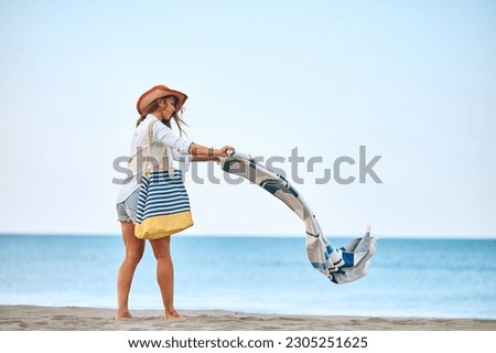 Full length of young woman spreading a towel on the beach. Copy space. Royalty-Free Stock Photo #2305251625