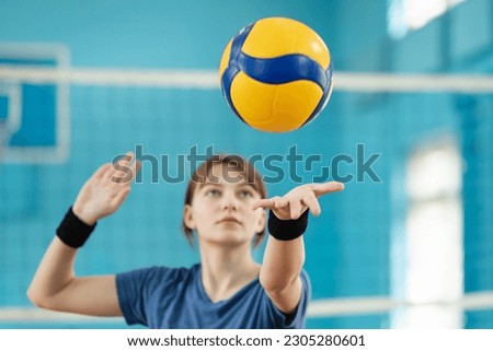 Photo in action of a young girl serving the ball. Learner practicing fundamental volleyball skill, serving the ball to opponents side Royalty-Free Stock Photo #2305280601
