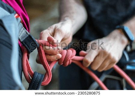 An alpinist tying a rope on his climbing equipment Royalty-Free Stock Photo #2305280875