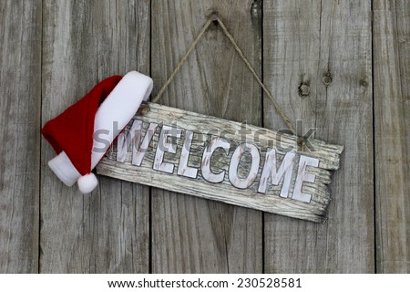 Wood welcome sign with Christmas Santa Claus hat hanging on old wooden background