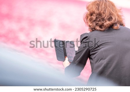 A female taking a picture by phone of a field with tulips