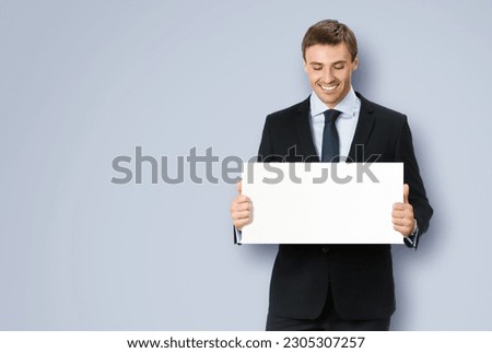 Photo of business man, employee, professional wear black confident suit, necktie. Businessman hold, show, demonstrate, advertise, promote empty white banner signboard. Isolated grey gray background