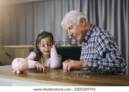 Money, piggy bank and help with child and grandfather for savings, investment and learning. Growth, cash and future with young girl and old man in family home for generations, finance and support Royalty-Free Stock Photo #2305309741
