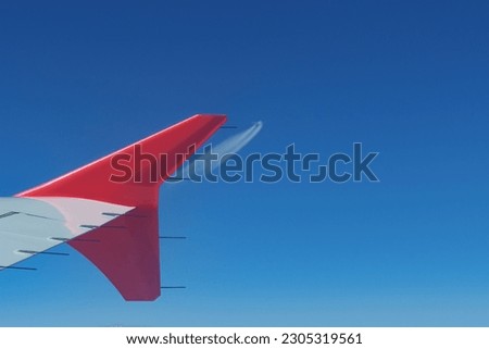 View of an airplane winglet during flight and incoming airplane in the distance. Aviation, aerodynamics and air traffic concepts Royalty-Free Stock Photo #2305319561