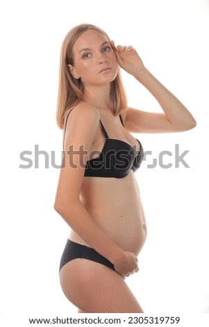 studio portrait of a beautiful pregnant woman on a white background in black underwear. a pregnant girl with a model appearance. pregnant blonde model. young happy mother