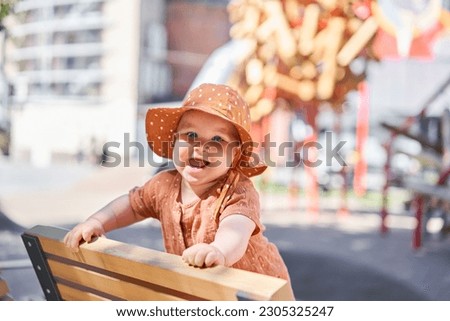 Portraits of a cute 10 months old baby girl. Walking on the playground, on a sunny summer day. Royalty-Free Stock Photo #2305325247