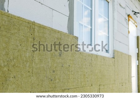 Facade insulation with mineral wool, thermal improvement and energy saving. Modern farmhouse renovation covering with stone wool panels close up. House insulation concept Royalty-Free Stock Photo #2305330973