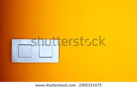 White plastic double electric light switch on the background of a yellow gradient texture wall with space for text.Selective focus.