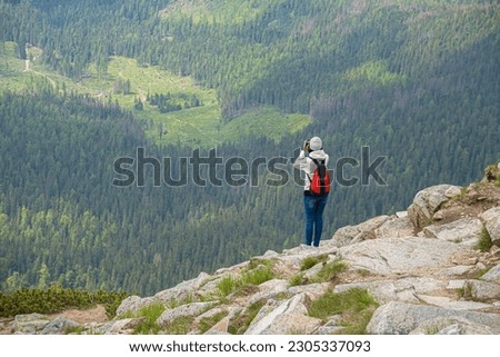 Young woman traveler on a high mountain with a photo camera.