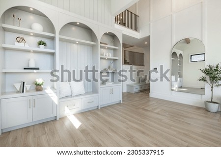 Living room interior with white decor arched mirror and built in shelving warm white tone minimalist Royalty-Free Stock Photo #2305337915