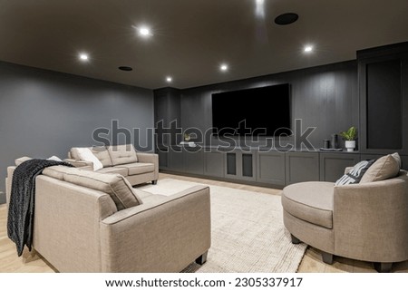 interior media room with dark grey walls comfortable furniture and large tv screen Royalty-Free Stock Photo #2305337917
