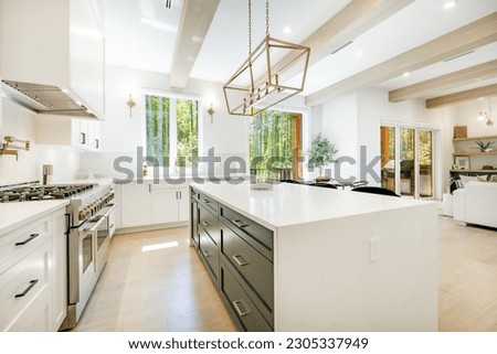 large modern farmhouse kitchen with white walls cabinets countertops bar chairs eating counter gold lighting fixtures stainless appliances and pot filler Royalty-Free Stock Photo #2305337949