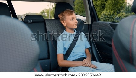 Little blond boy in a blue shirt opens passenger door in car, sits down and fastens his seat belt before starting the trip Royalty-Free Stock Photo #2305350449