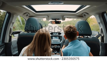 Rear view. Children boy and girl sitting in back seat of car during family trip. Happy family is driving a modern car Royalty-Free Stock Photo #2305350575