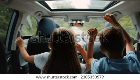 Two little boy and girl listens enjoys music and dancing while road trip. Children are playing in the car. Concept of journey. Royalty-Free Stock Photo #2305350579