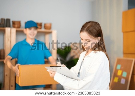 Caucasian entrepreneur woman sign paper on clipboard after use delivery quick service door to door at home office with worker man holding cardboard background