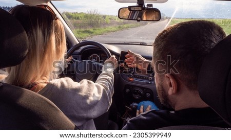 A driving instructor helps a woman learn how to drive a car. A woman is driving a car for the first time with an instructor and is very worried. Summer car driving training concept. Law exam. Royalty-Free Stock Photo #2305399949