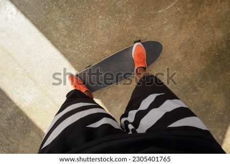 Point of view shot of skateboarder rides on skateboard in orange sneakers.   Royalty-Free Stock Photo #2305401765