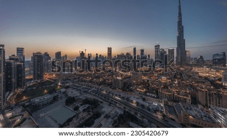 Dubai Downtown day to night transition timelapse with tallest skyscraper and other towers panoramic view from the top during sunset in Dubai, United Arab Emirates. Lights turning on.