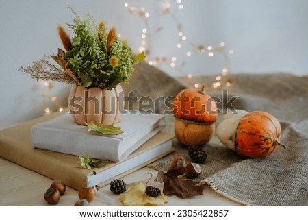 Autumn composition of books, pumpkins, nuts, autumn leaves, a bouquet of dried flowers, cones. Pumpkin and nuts. Garland with warm light. Bokeh. Thanksgiving Day. Festive composition.