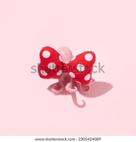 Pink painted octopus with a cute romantic hair bow, creative layout, summer girly fashion trend idea, candy pink background.