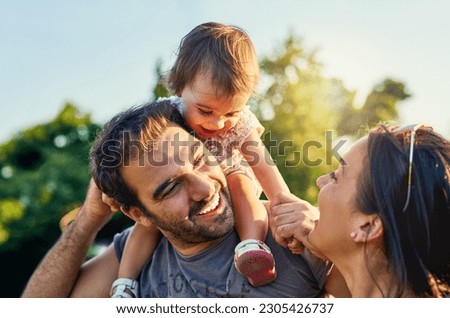 Family, father and daughter on shoulders in park with happy mom, love and summer sunshine. Young couple, baby girl or laugh together for freedom, bond and helping hand for care, backyard or garden Royalty-Free Stock Photo #2305426737