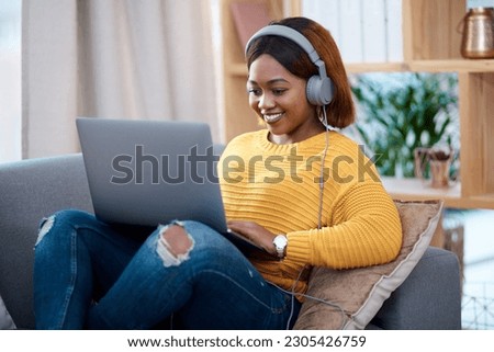 Black woman with laptop, headphones and relax on sofa, search online for movie and streaming subscription at home. Happy African female person in apartment, connectivity and watching on pc with web Royalty-Free Stock Photo #2305426759