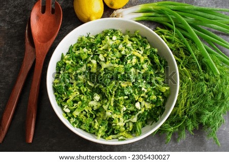 Maroulosalata Greek Lettuce Salad with Salad Tongs: Overhead view of a serving bowl of Greek lettuce salad with feta cheese Royalty-Free Stock Photo #2305430027