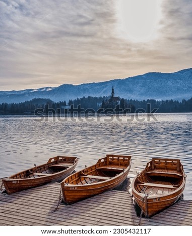 Wooden boats, island church and snow on the mountain, Bled, Slovenia
