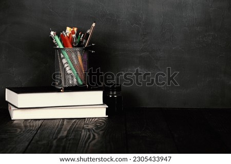 School and education concept.Copy space. Chalk board and old books. Pens and pencils in a bucket. Fountain pen and ink on a wooden table.Chalk rubbed out on blackboard. Chalkboard background.