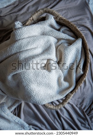 rattan basket with a white cloth blanket inside it for newborn photoshoot