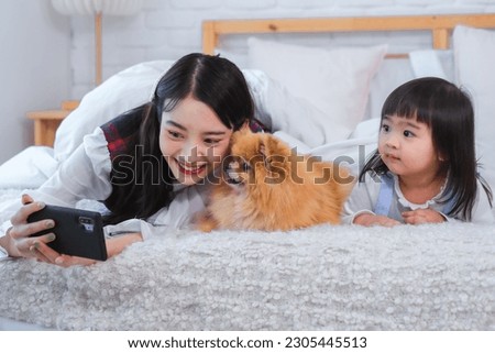 A grin spread across the asian girl's face as she captured the sweet and heartwarming image of the little girl and the dog on her phone.