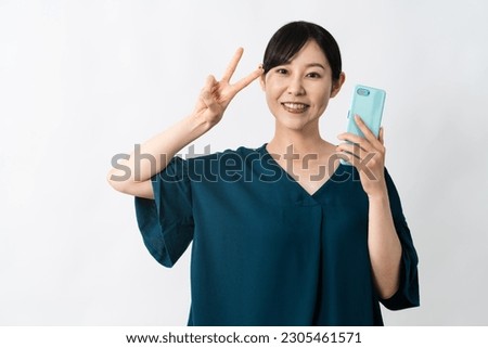 A young woman doing a peace sign while holding a smartphone