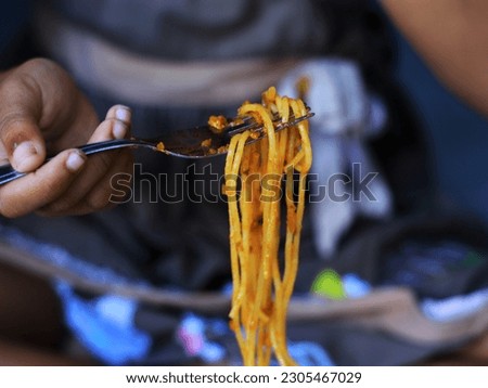 Defocused of close up daughter eat spaghetti with garp, spaghetti lifted and long.