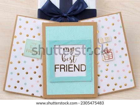 Three "my best FRIEND" postcards on a light brown wood texture background, with a blue bow on top