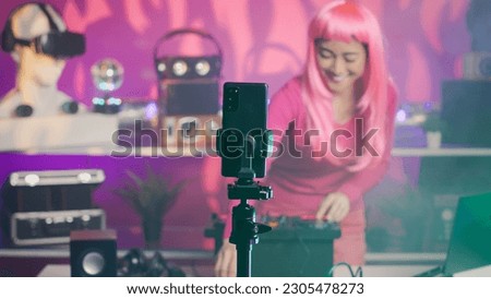 Performer recording song process with phone camera, mixing and mastering electronic sound preparing eletronic album. Dj artist performing techno music using professional audio equipment