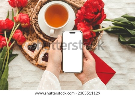 Mobile phone and spring flower tulips on a festive background. Theme of love, mother's day, women's day flat lay.