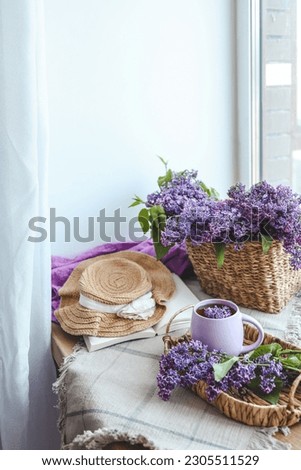 Cup of tea, straw hat and lilac basket, spring still life.