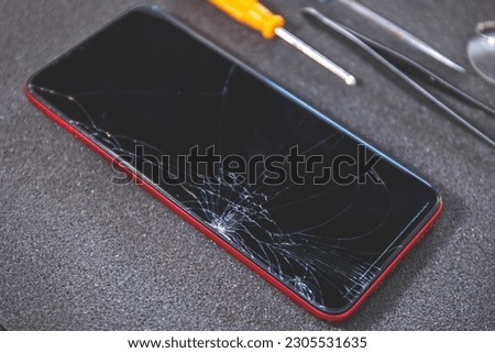 Red Mobile smart phone with broken damaged display. Modern smartphone with damaged glass screen. Device needs repair.