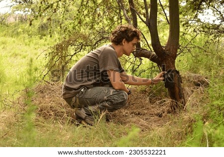 A male wildlife biologist setting a camera trap on a tree