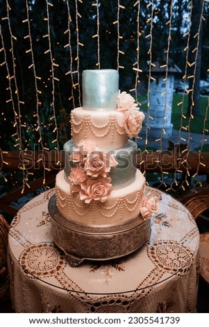 Tall beautiful wedding cake for the newlyweds on the festive table. Creative image for your design or illustrations.