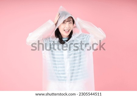 Asian woman smile and wearing a rainproof coat over pink background