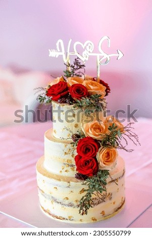 Beautiful white wedding cake decorated with orange and red roses close up